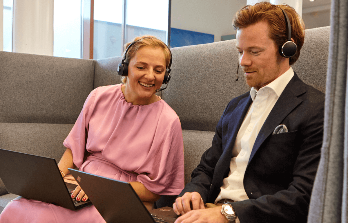 Bilde av to smilende kollegaer i en sofa