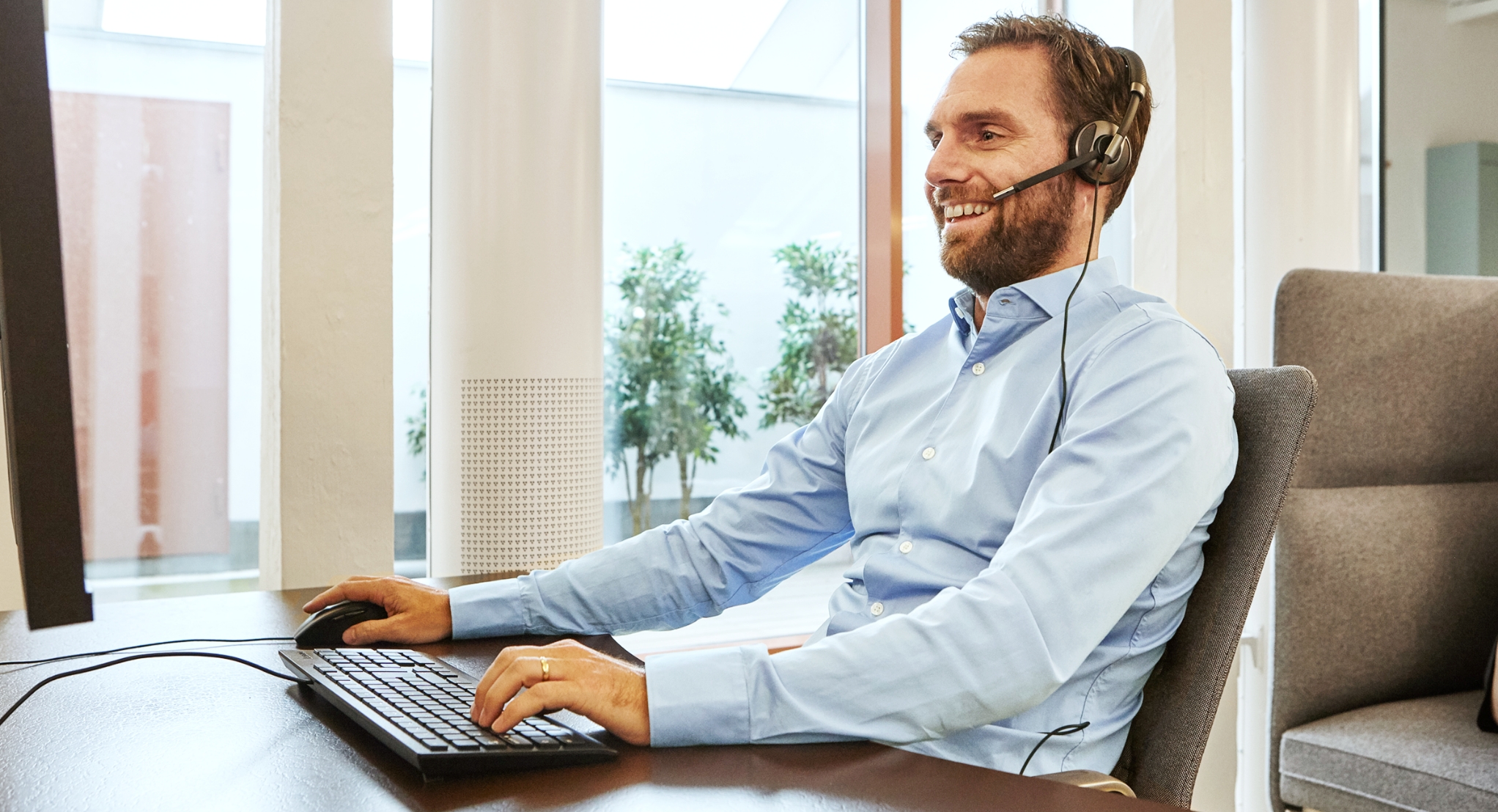 Bilde av service medarbeider med headset foran pc