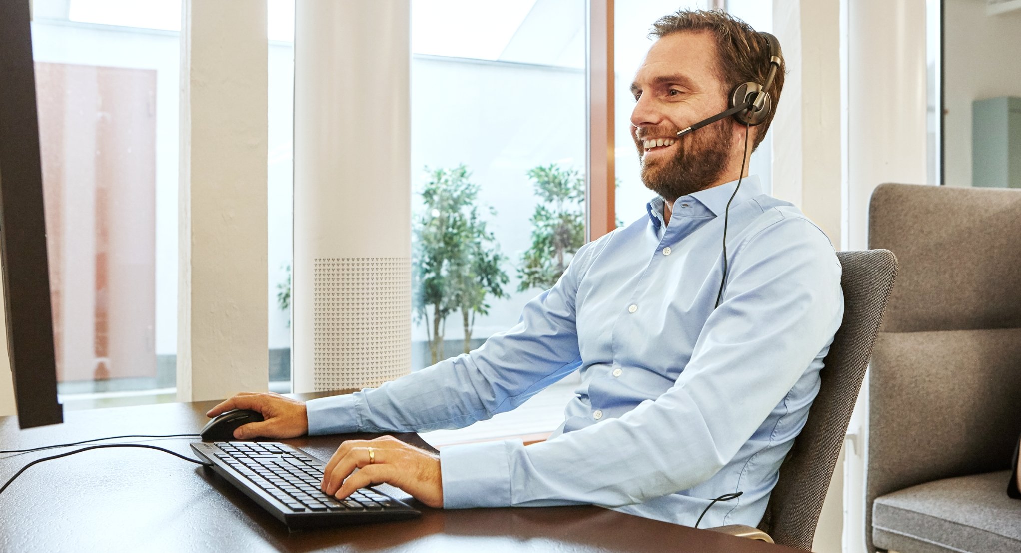 Bilde av service medarbeider med headset foran pc